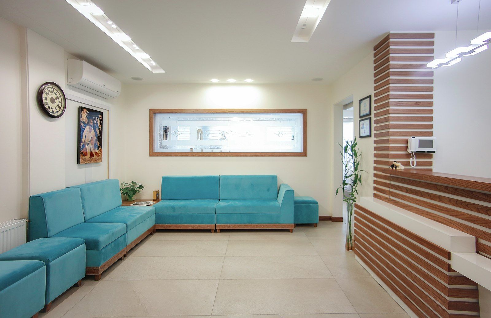 A clinic reception with teal sofas and a wooden counter